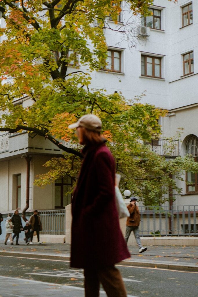 a woman walking across a street next to a tall building